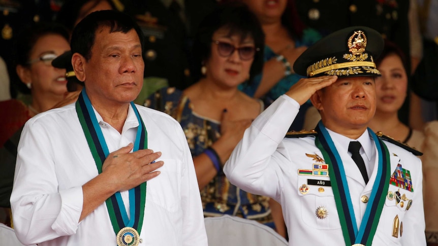 Philippine President Rodrigo Duterte stands to attention next to Armed Forces chief General Eduardo Ano.
