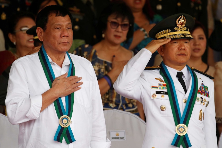 Philippine President Rodrigo Duterte stands to attention next to Armed Forces chief of staff General Eduardo Ano.