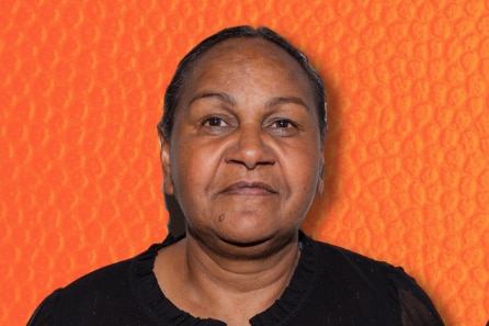 A headshot of a woman in front of a textured orange backdrop