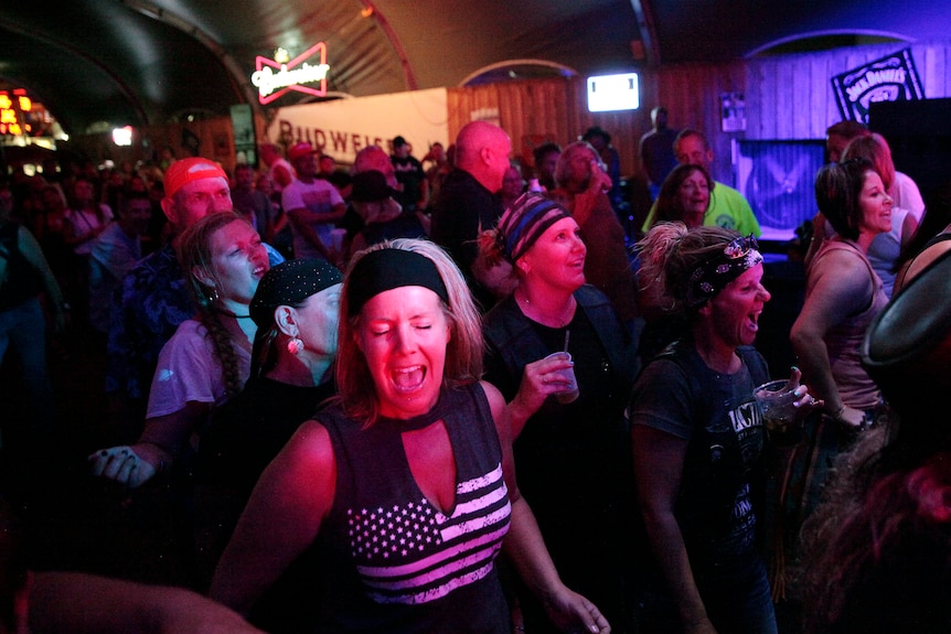 Ludzie tańczą w zatłoczonym barze.