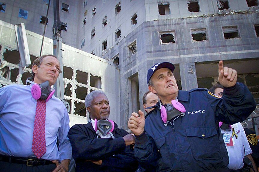 Rudy Giuliani pointing something out while standing near the rubble of the World Trade Centre