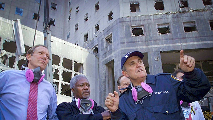 Rudy Giuliani pointing something out while standing near the rubble of the World Trade Centre