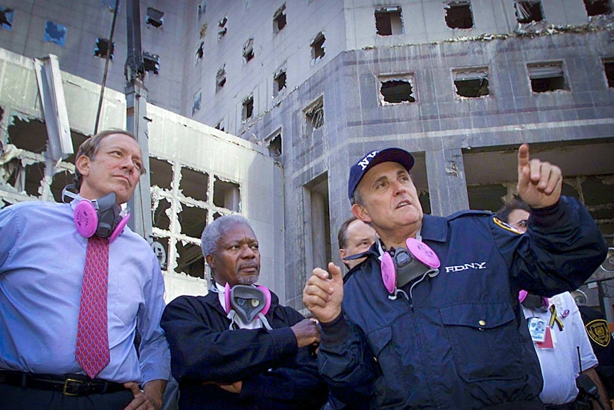 Rudy Giuliani pointing something out while standing near the rubble of the World Trade Centre