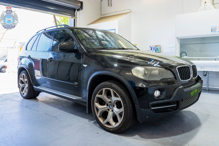 Un SUV noir garé à l'intérieur d'un entrepôt. 