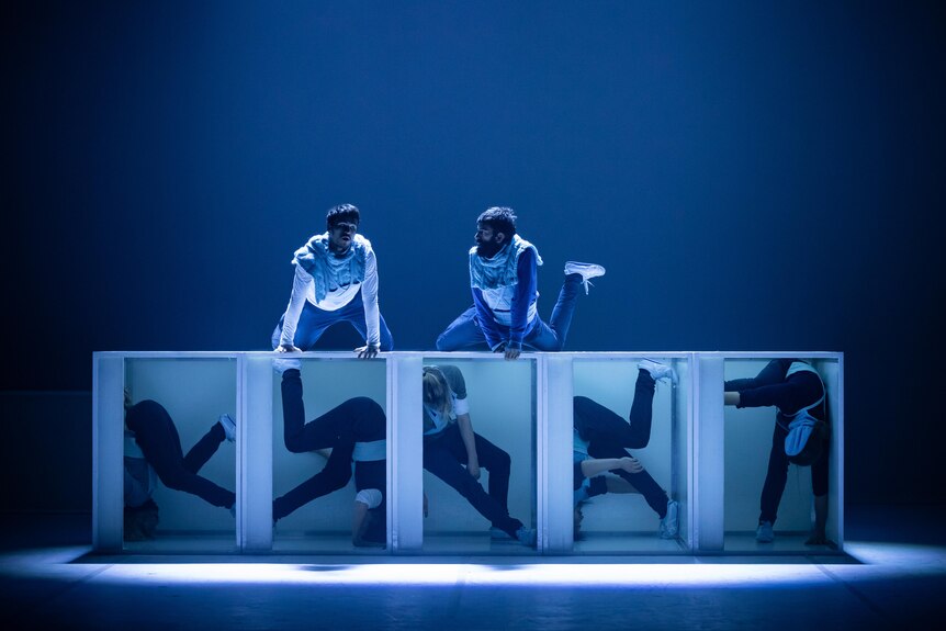 A group of people dancing on stage using large white cubes