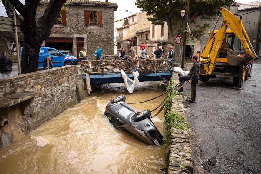 Car being hoisted out of a river following flash flooding