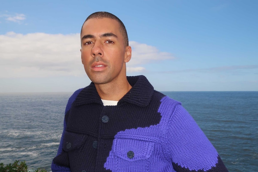 Young man in a knitted jacket by the beach.