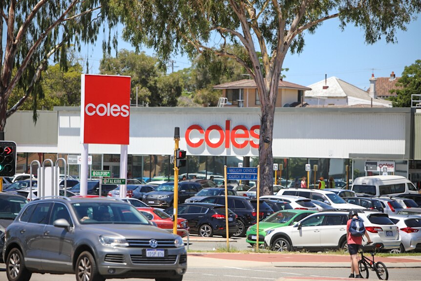 The exterior of a coles supermarket with bright red signage and cars in the car park.