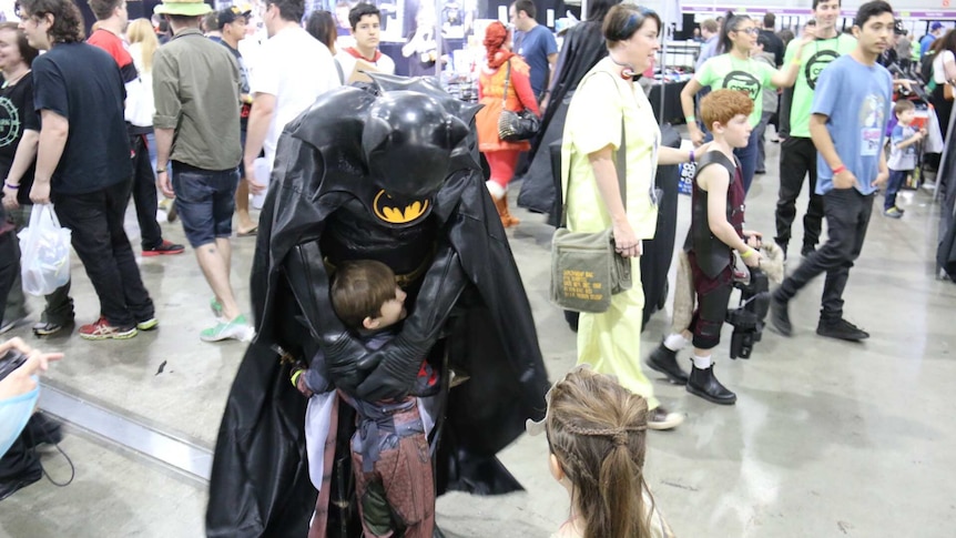 Batman gets a hug from a young person