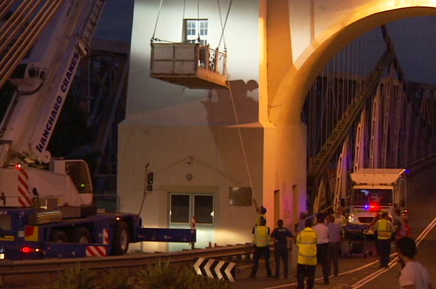 Crane hanging in front of the window of the Walter Taylor bridge, and emergency crews gathered on the road beneath.