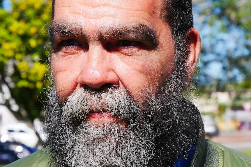 Close up picture of a bearded Aboriginal elder staring into the distance.