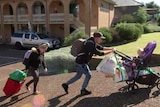 Homeless family with stroller and carrying bags.
