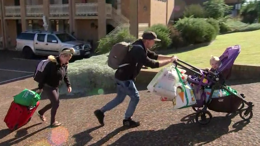 Homeless family with stroller and carrying bags.