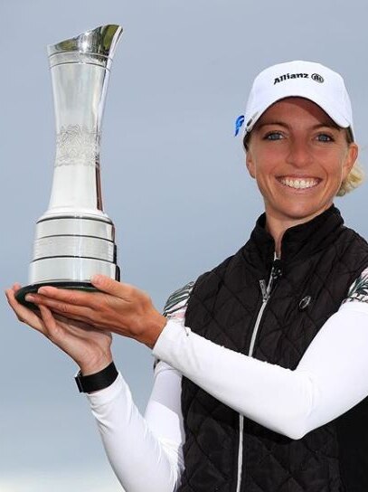 A smiling golfer holds the trophy after she wins a major title in Scotland.