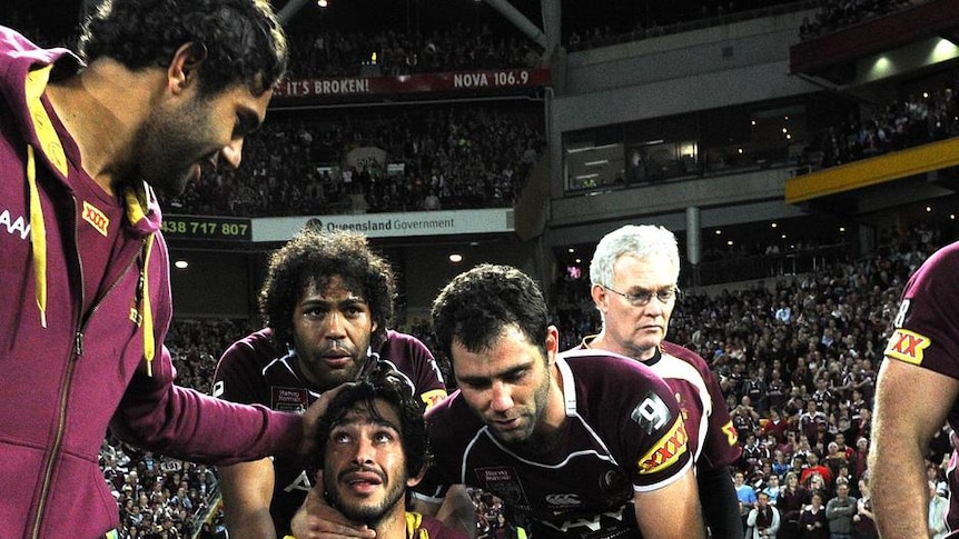 Injured Johnathan Thurston is consoled by his Maroons team-mates after the siren.