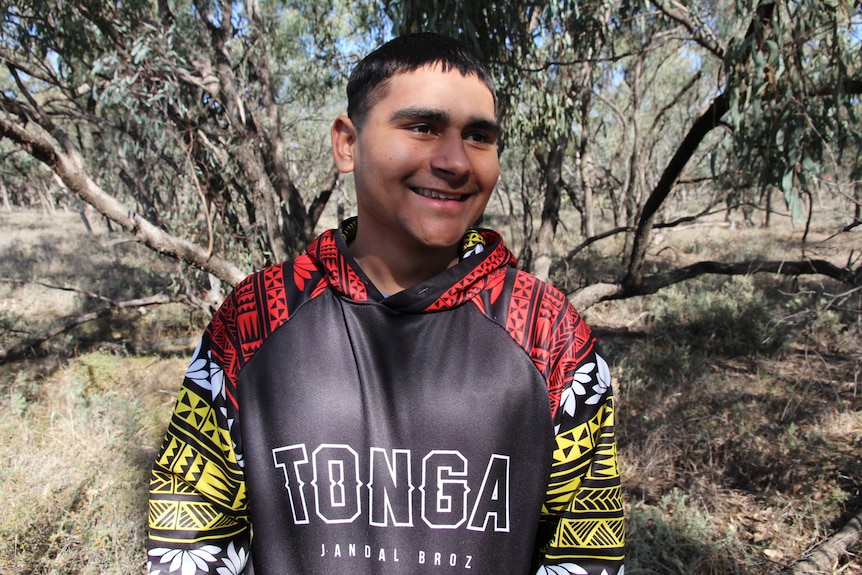 A smiling young man, dressed for warmth in the bush.
