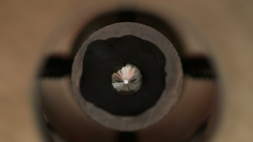 A close up of a diamond mounted on an industrial drill bit.