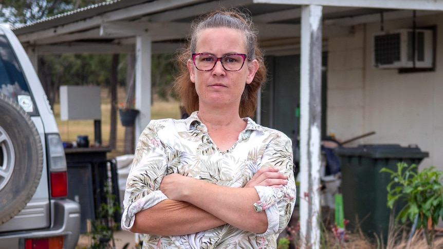 A woman stands with her arms crossed.