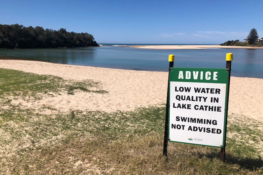 A low water quality sign in front of a lake.