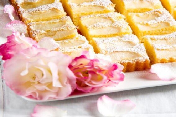 Golden cake slices are displayed on a white platter with a pink rose as decoration.
