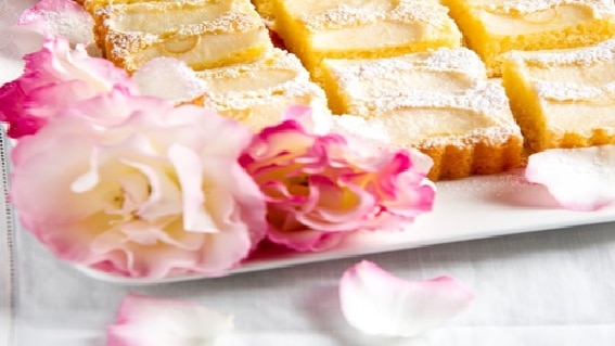 Golden cake slices are displayed on a white platter with a pink rose as decoration.