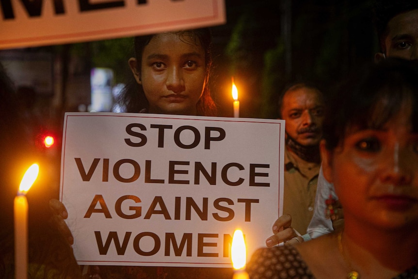 A young woman holding a sign reading "stop violence against women"