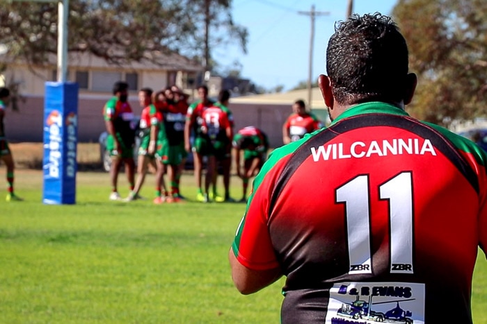 Wilcannia Boomerangs player looking at a group of other players.