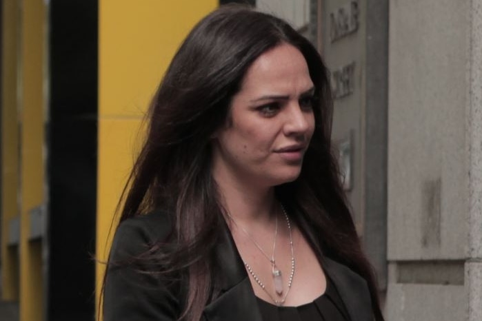 Violetta Esposito is dressed in black and walks away from the camera into court.