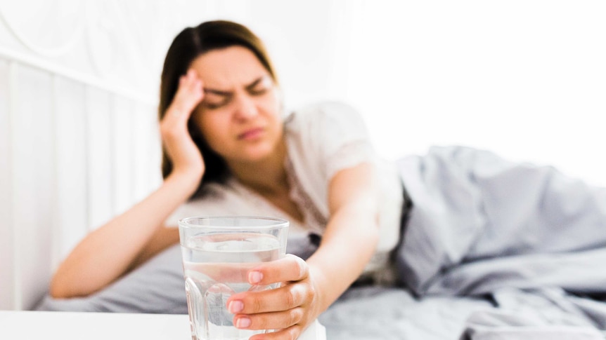 Woman in bed reaching for glass of water