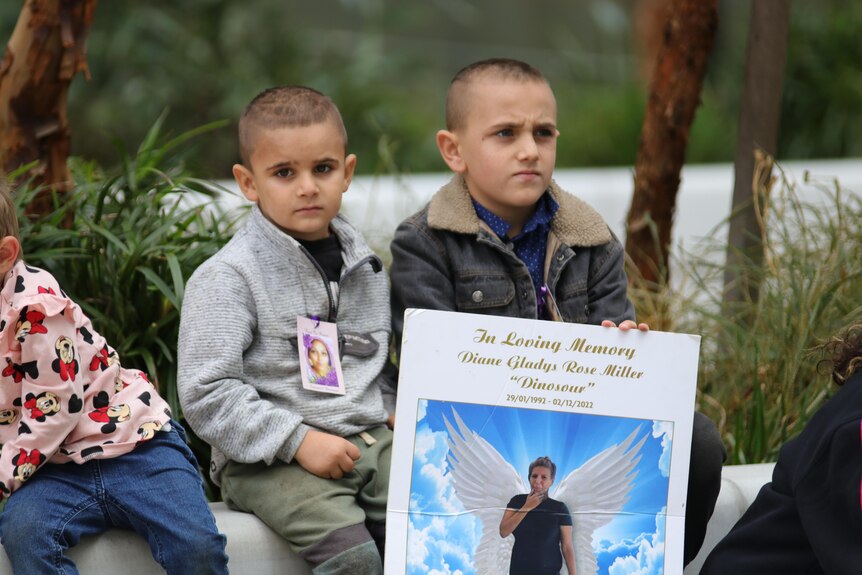 Two boys hold a sign in memory of Diane Miller.