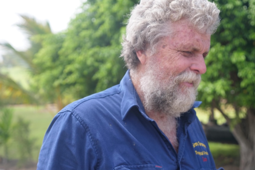 Fruit producer Ian Groves smiles and looks at the ground, with greenery in the background