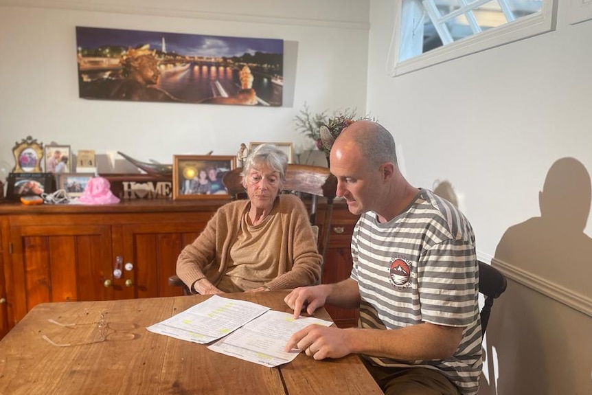 Angela and Alex Fitzwater sit at a table in a home, looking at papers.
