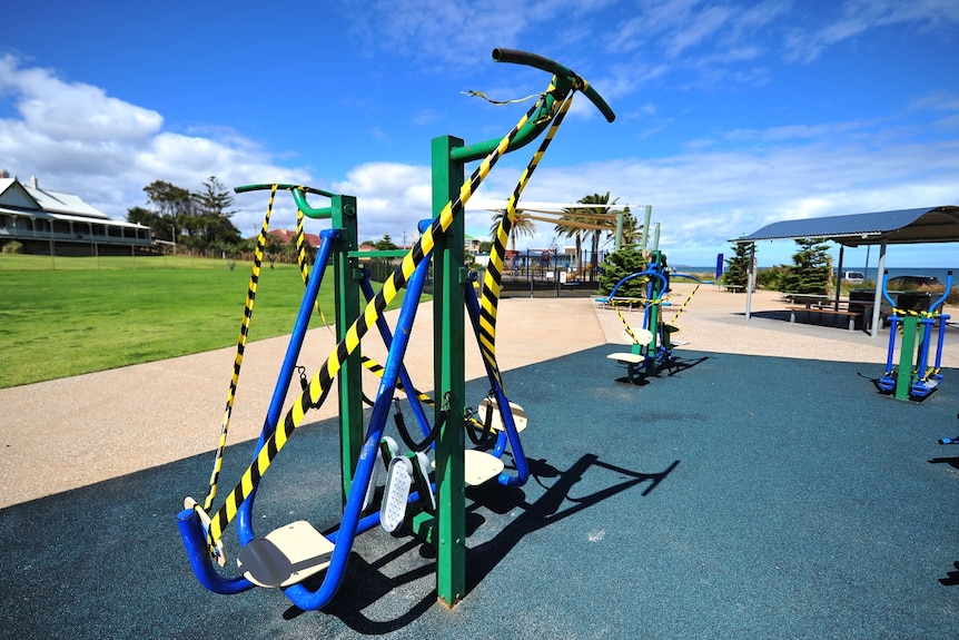 Outdoor public exercise equipment covered in yellow and black striped tape