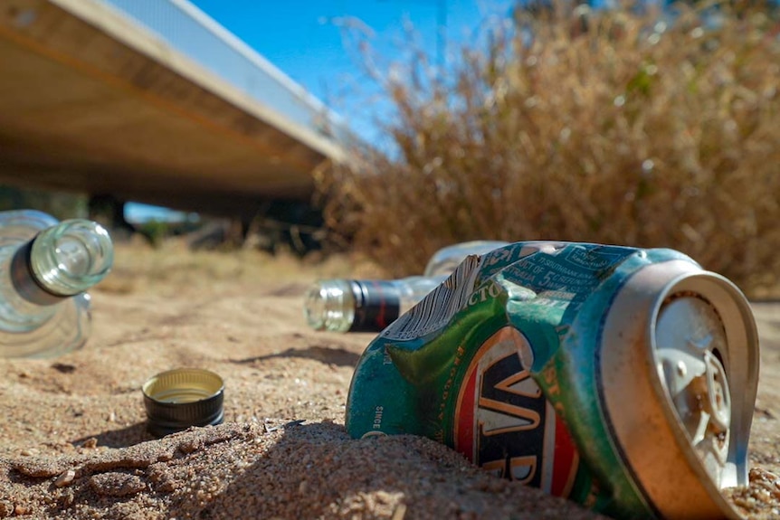 Empty liquor bottles and cans lay in the dry Todd River. 