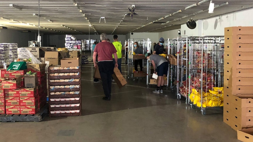 A warehouse with boxes of food stacked and people in the background.