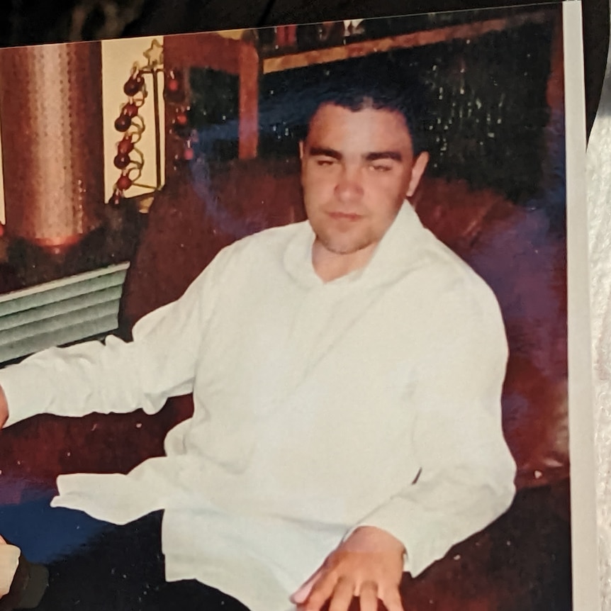 A photo of a man in a white shirt sitting on a recliner