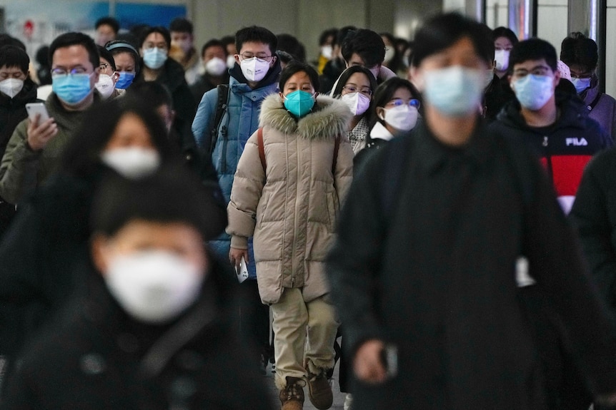 A crowd of people in winter coats and face masks