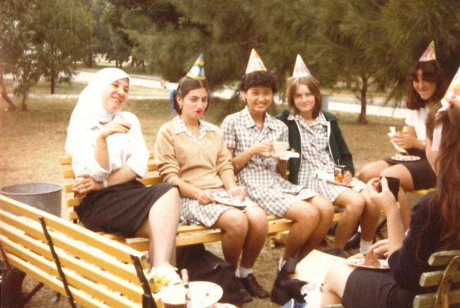 Scanned image of five girls wearing party hats in a schoolyard in Randwick in the 1980s.
