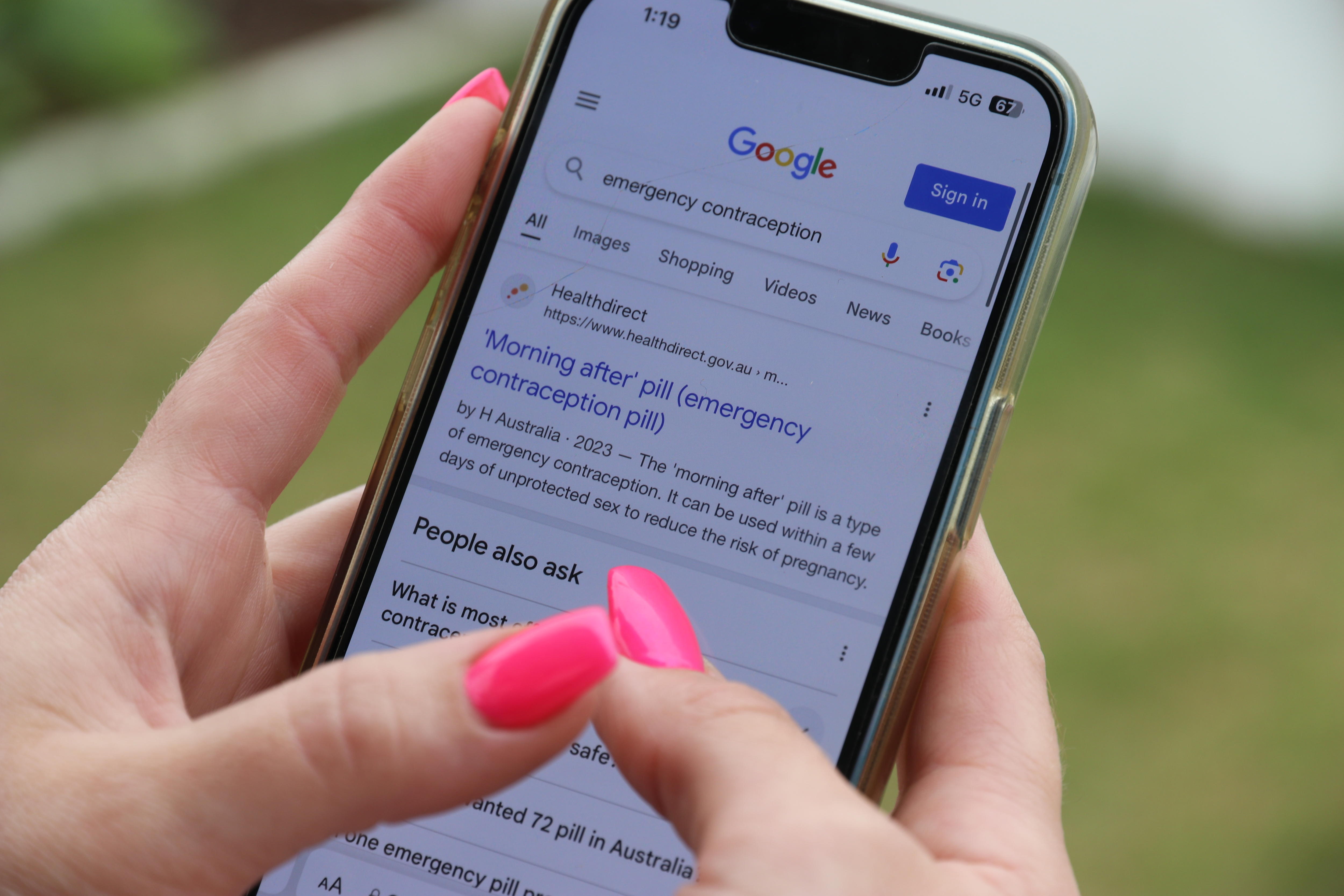 a hand with pink fingernails searches for emergency contraception on an Iphone