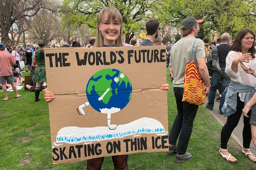 A girl holds a sign saying "the world's future"