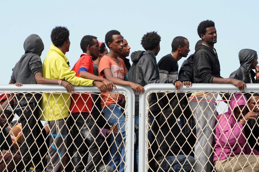Migrants wait to disembark from military ship Bettica