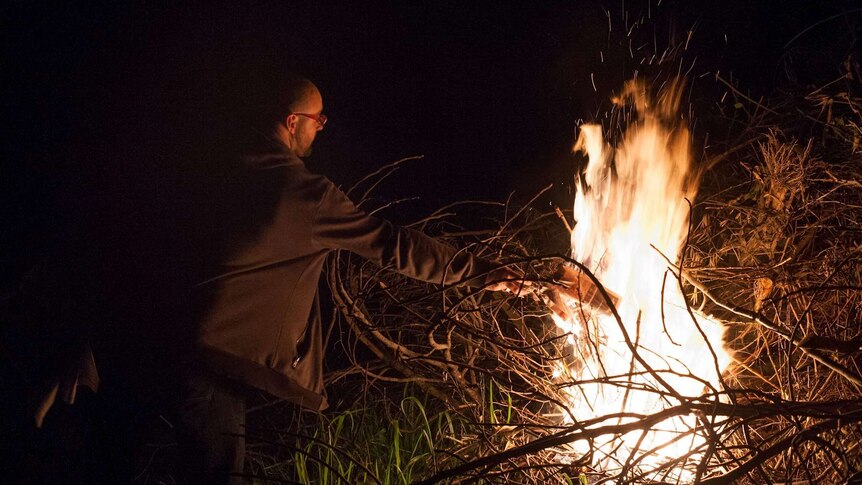 Man fuelling bonfire with paper.