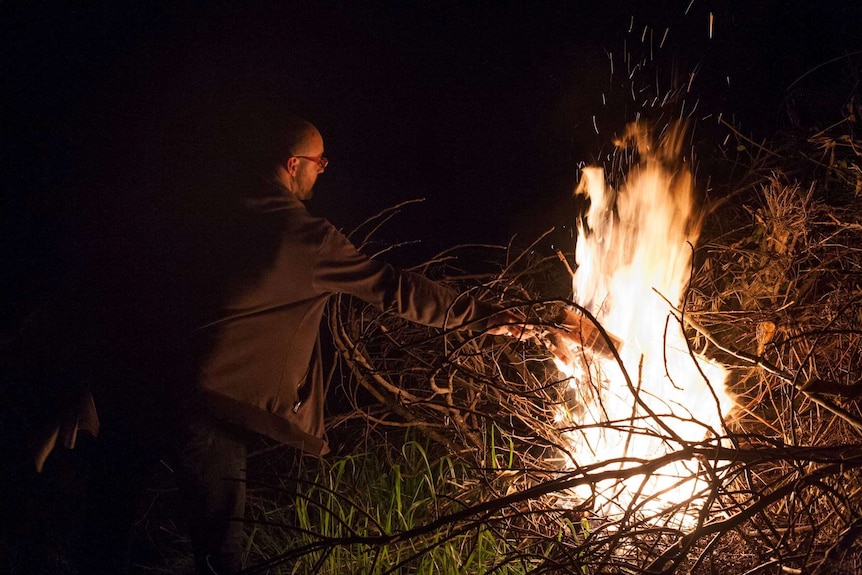 Man fuelling bonfire with paper.