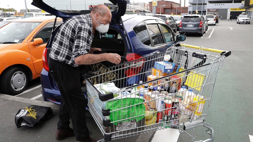 A man unpacks his shopping trolley in the carpark at a supermarket in central Christchurch, New Zealand.