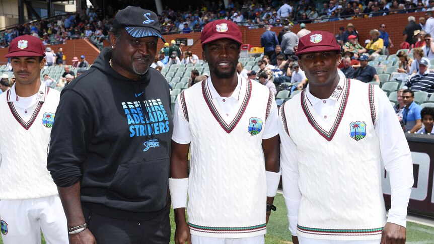 A former West Indian cricketer stands smiling next to two cricketers making their Test debuts at Adelaide Oval.