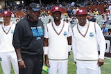 A former West Indian cricketer stands smiling next to two cricketers making their Test debuts at Adelaide Oval.
