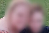 Blurred image of a woman and a man sitting on grass