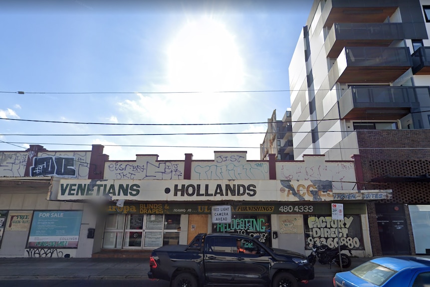 The shopfront of an abandoned building, with an apartment block next to it.