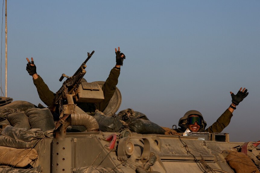 Two soldiers gesture the peace sign from a tank