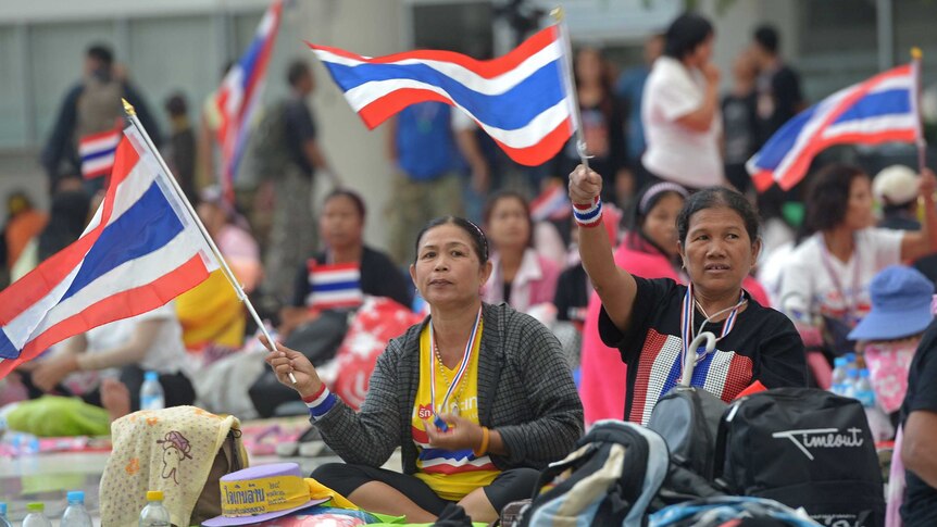 Thai anti-government protesters wave national flags as they rally in Bangkok